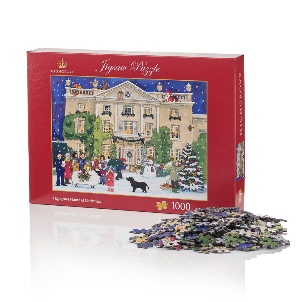 A red 1000-piece jigsaw puzzle box featuring a festive Christmas scene of a grand highgrove house with people, trees, and a black dog in the snow. A pile of cut puzzle pieces sits in front of the box on a white reflective surface.