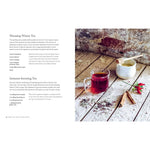 Red tea in a glass mug on a wooden surface with cinnamon sticks and a white container.