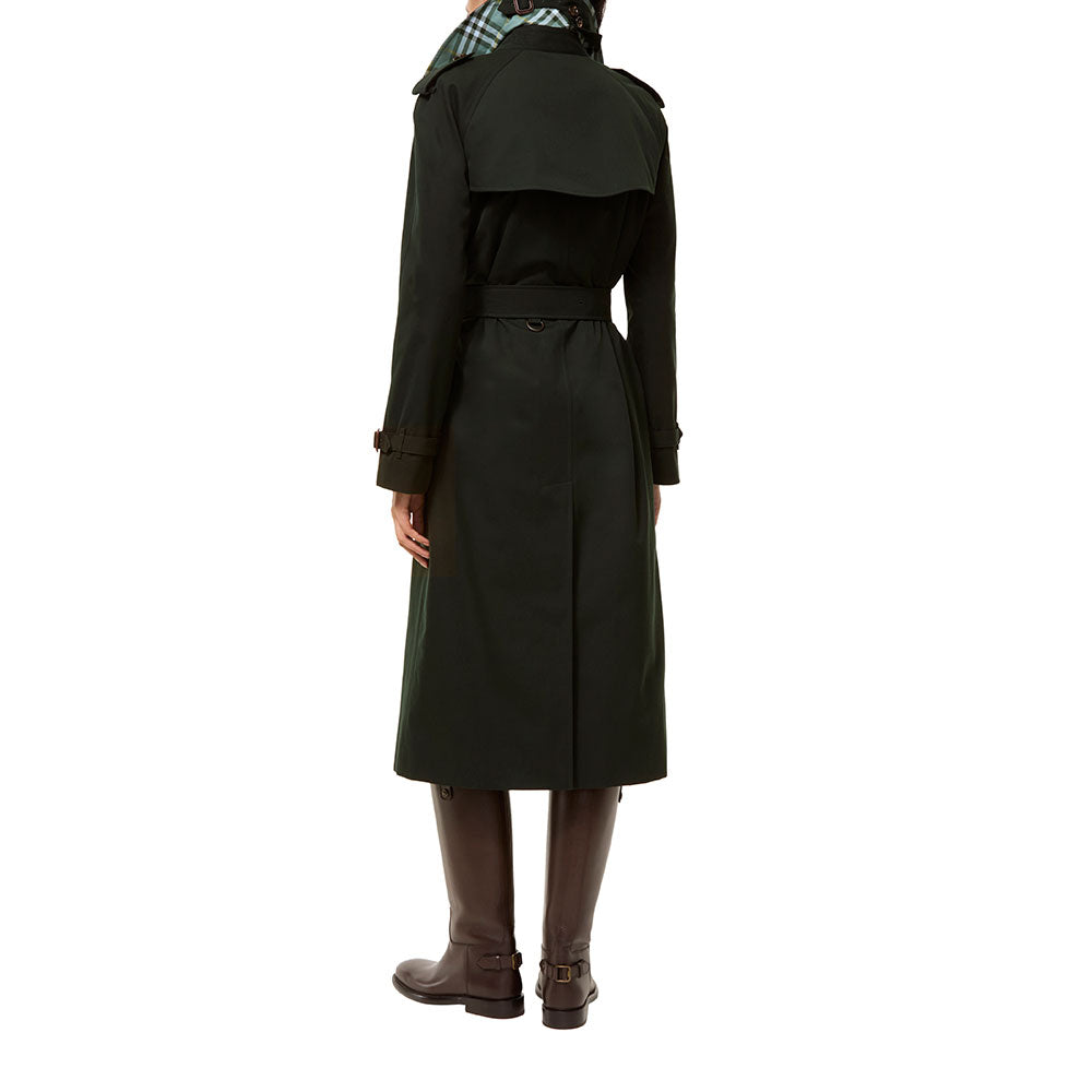 A person shown from the back wearing a long dark green trench coat with a belt, brown knee-high boots, and a green plaid neck gaiter, against a plain white background.