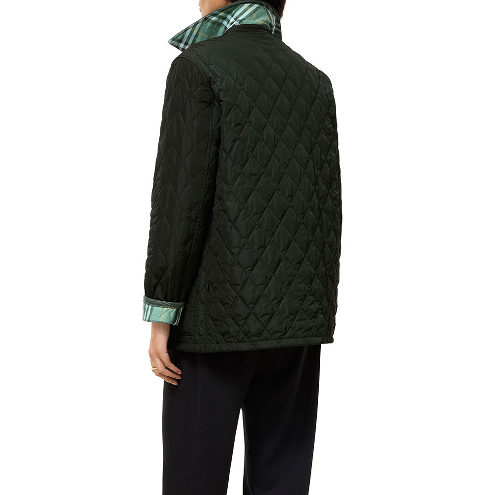 A person shown from the back wearing a dark green quilted jacket with a green and white plaid collar and dark trousers, against a plain white studio background.