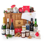 A festive Christmas hamper basket containing a variety of gourmet foods and drinks, including wine, whisky, port, Christmas pudding, shortbread, butter fudge, and a spice bag. The basket is adorned with a Highgrove crown plaque and Christmas decorations.