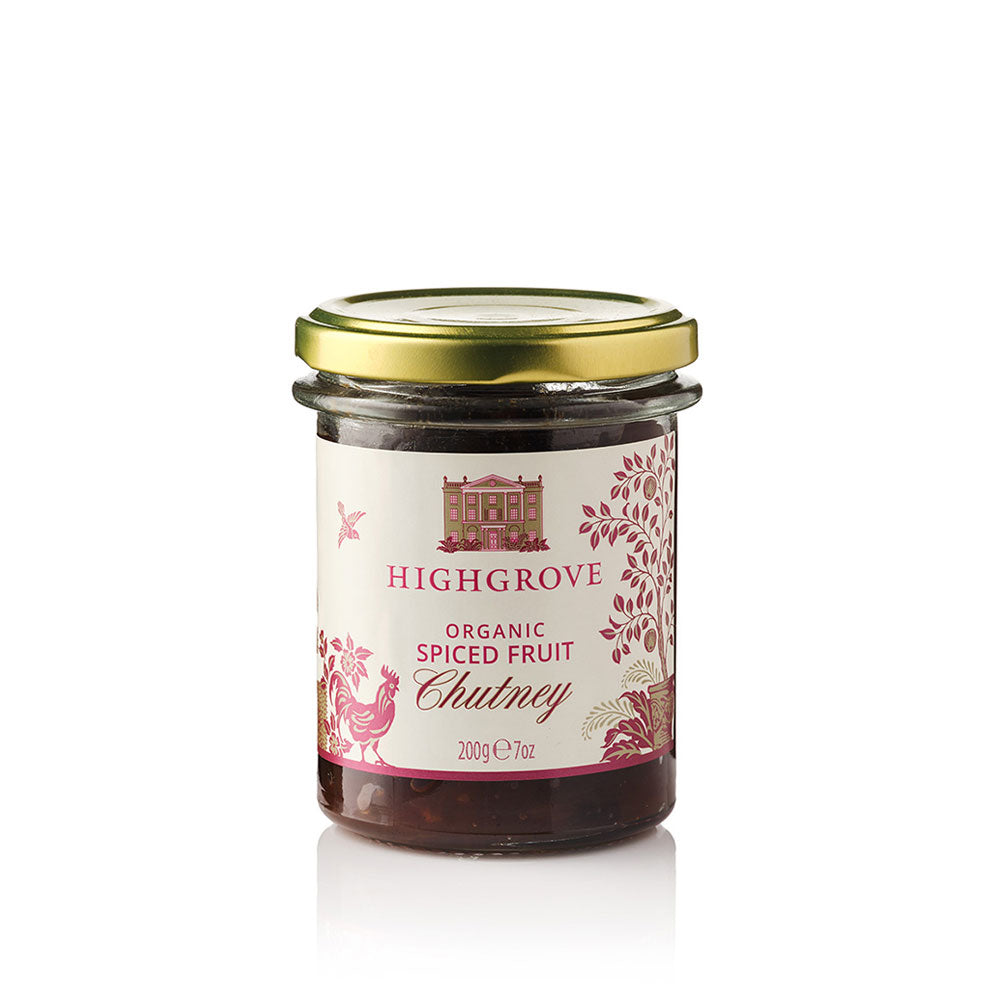 A glass jar of Highgrove Organic Spiced Fruit Chutney with a gold metal lid and a cream-colored label decorated with pink illustrations, set against a plain white background.