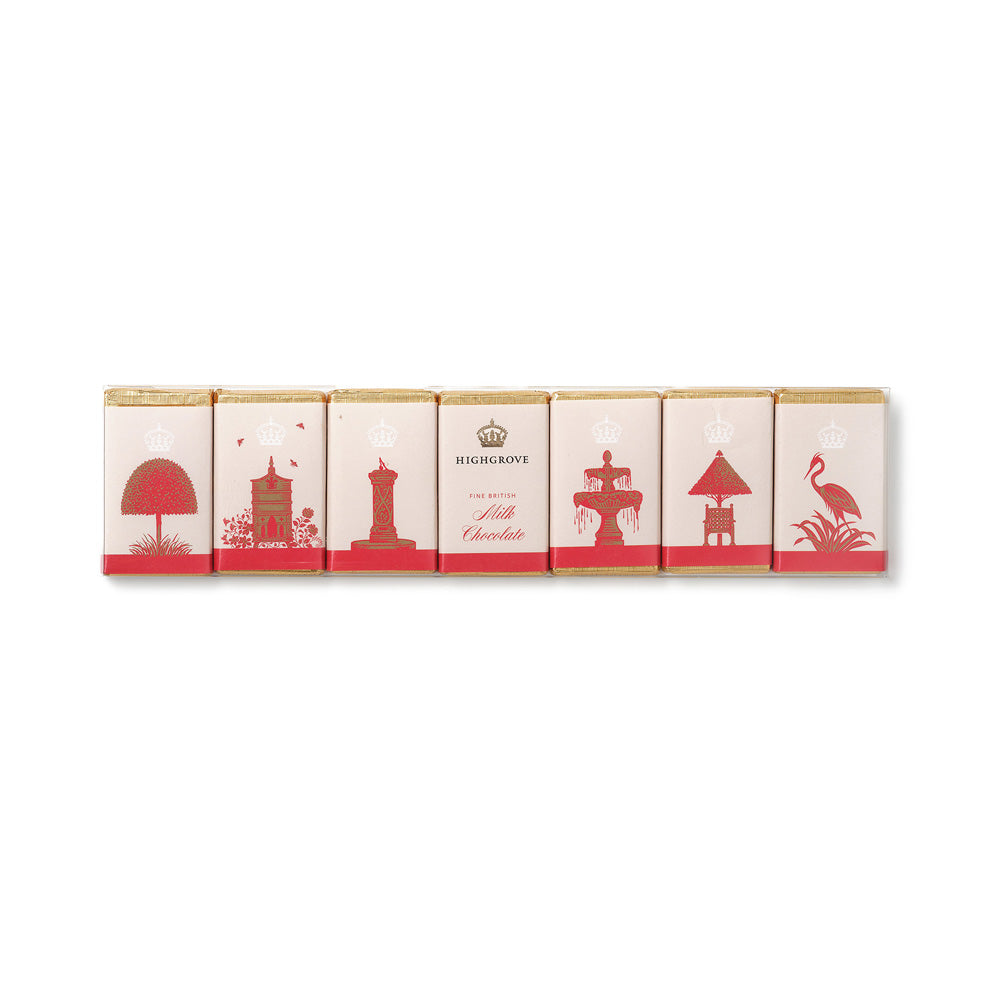 Six individually wrapped milk chocolate bars arranged in a row on a plain white background. The wrappers are cream-colored with red silhouettes of coastal landmarks and the brand name 'MILK CHOCOLATE' is visible on the centre wrapper.