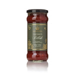 A glass jar of Highgrove Something to Relish spise tomato and warming chilies, featuring a dark olive green label with gold lettering and a black lid, set against a clean white background with a soft reflection.