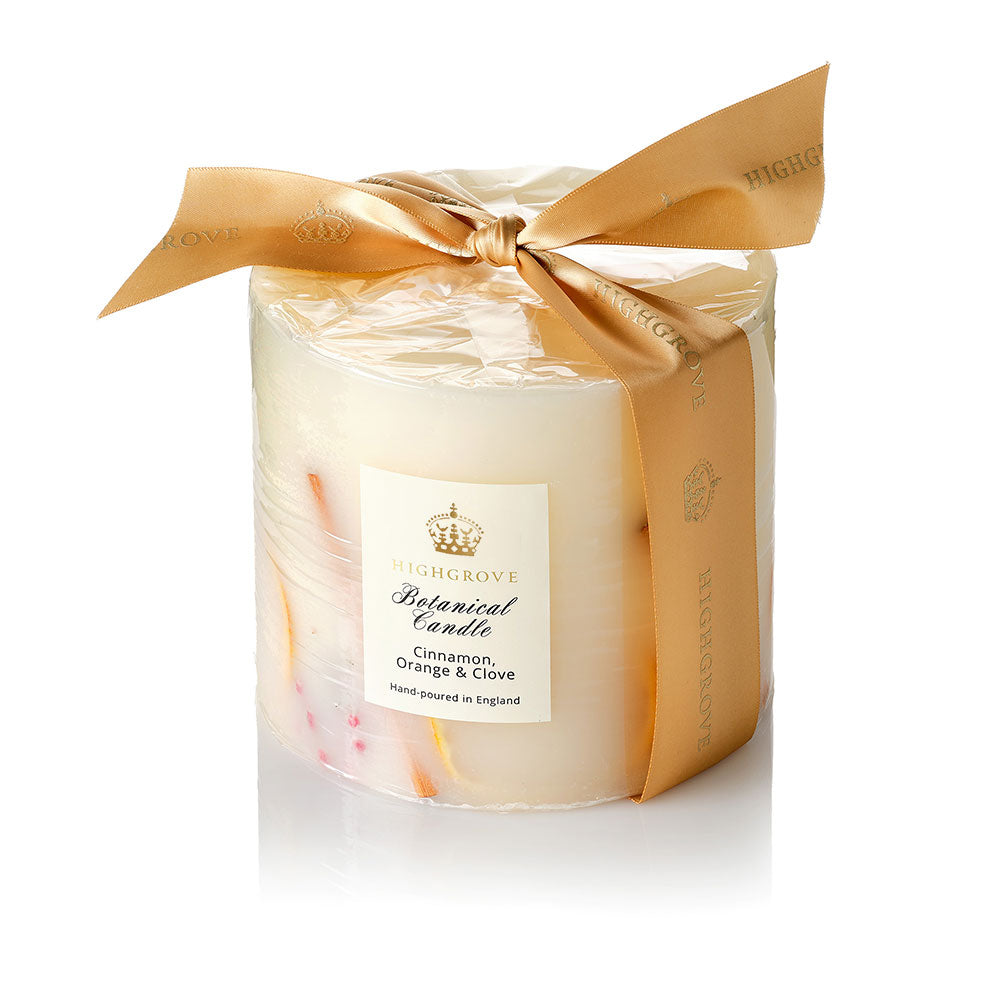 Three wick candle wrapped in gold paper with a bow on a white background