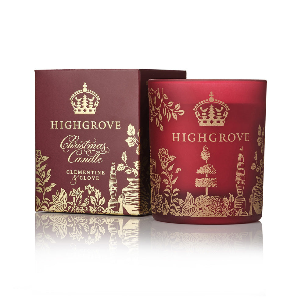 Highgrove Christmas Candle in Clementine & Clove scent, shown with its dark burgundy packaging box and the frosted glass candle jar decorated with gold illustrations and the brand name.