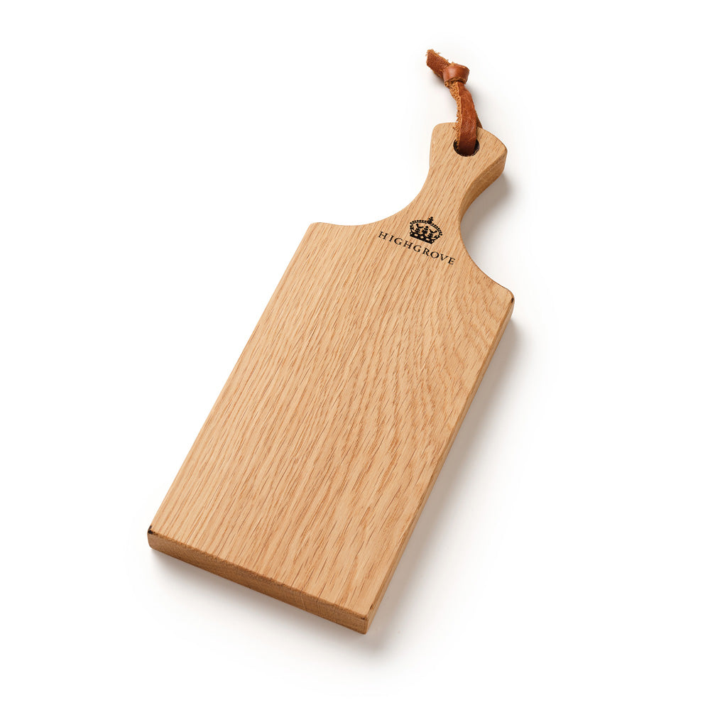 A rectangular wooden serving board with a handle, featuring a natural oak wood grain and the Highgrove crown and text engraved near the top. The board is suspended from a brown leather loop, set against a clean white background.