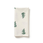 White napkin with green fern patterns on a white background