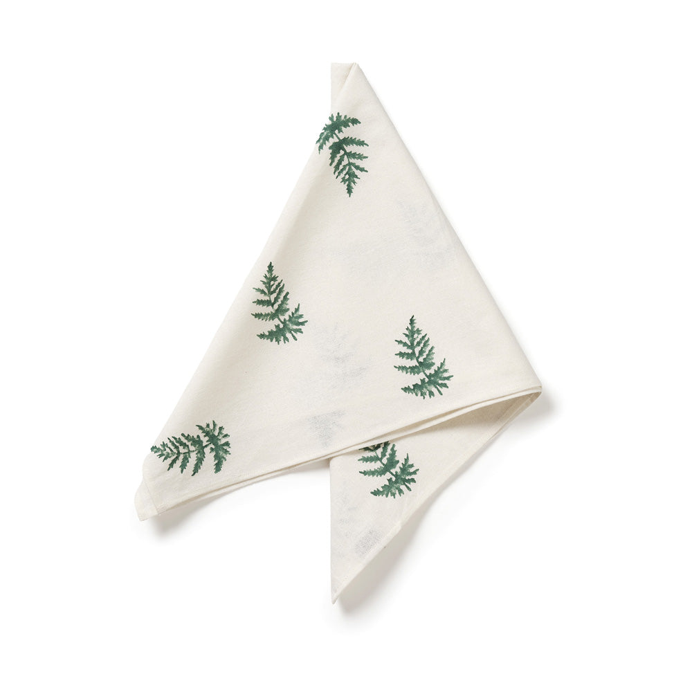 Folded white napkin with green fern patterns on a white background