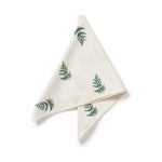 Folded white napkin with green fern patterns on a white background