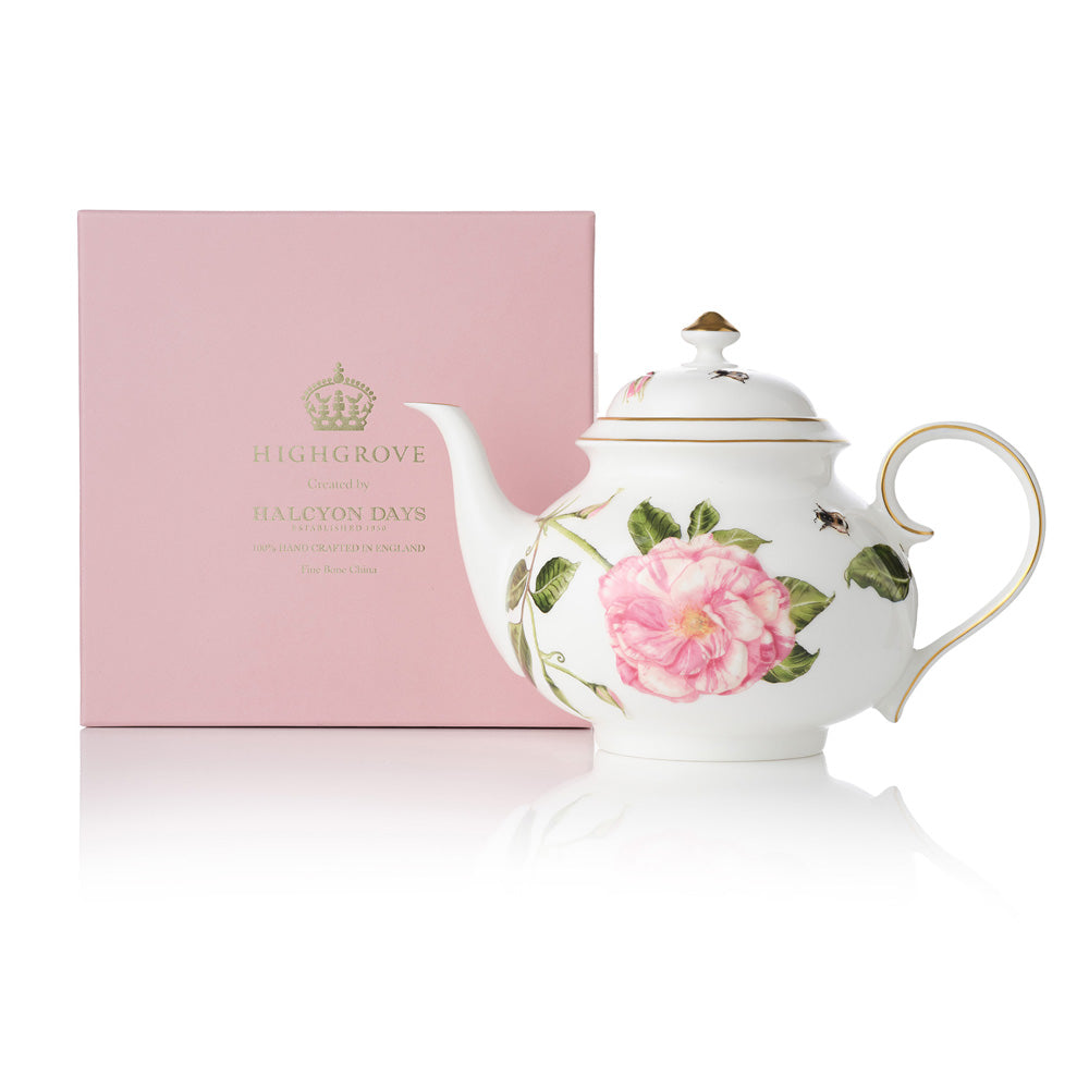 White teapot with The King's Rose floral design next to a pink box with gold 'Highgrove' writing on a white background