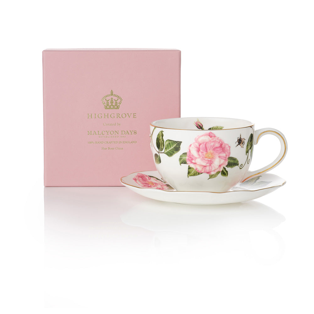 Teacup with The King's Rose floral design and matching saucer on a white background, next to a pink box with gold 'Highgrove' writing.
