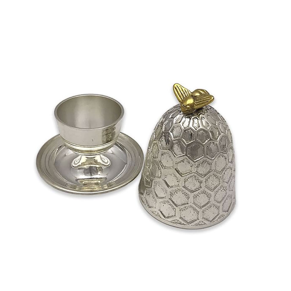 A silver-toned metal cup with a matching saucer and lid, featuring a textured honeycomb pattern on the lid and a small gold-toned bee accent on top, shown on a plain white background.