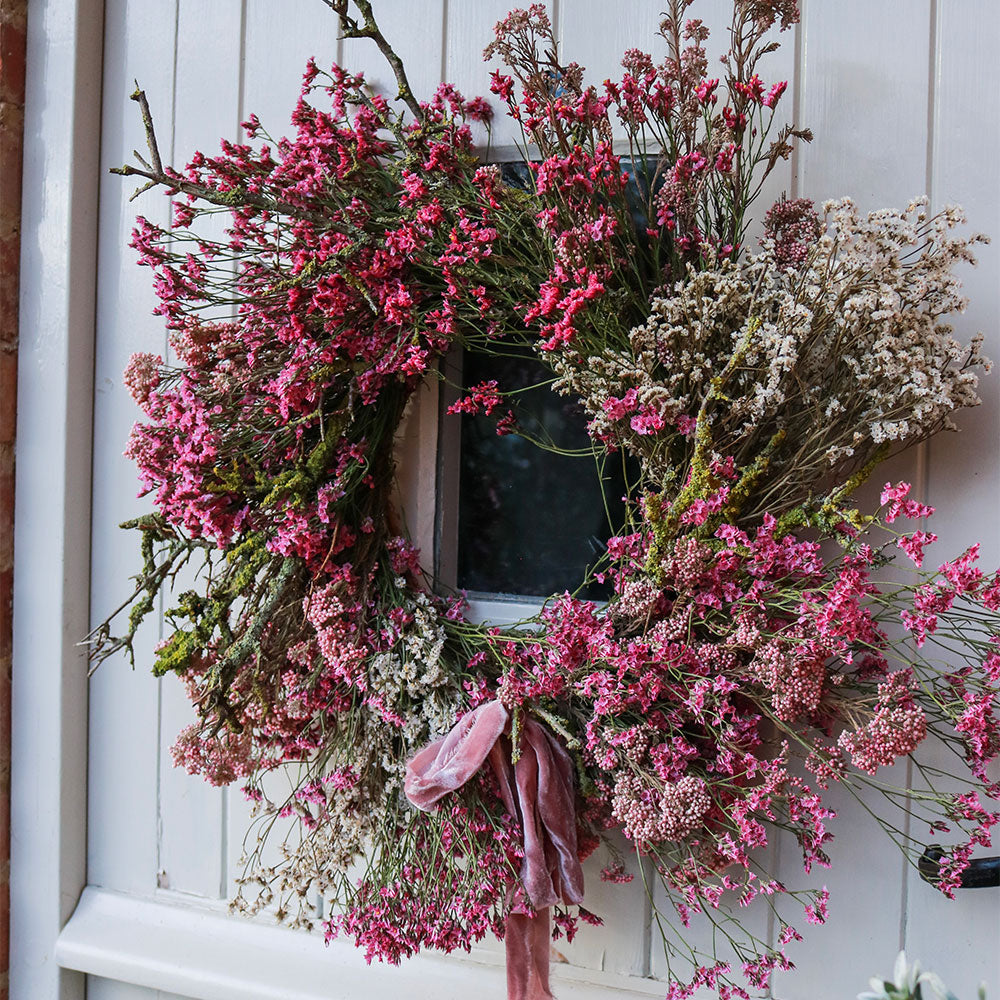 Floral wreath with pink and white flowers on a white door