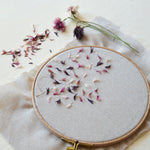 Embroidery hoop with dried flowers on a light fabric background