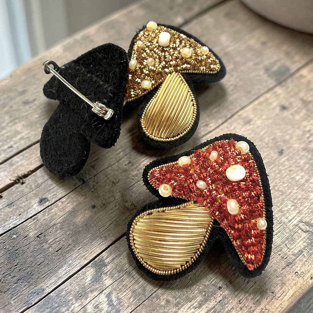 Two decorative mushroom-shaped pins on a wooden surface