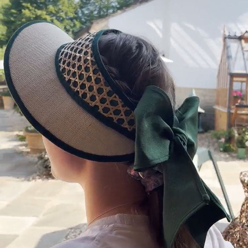 Emily Hurst wearing a visor with a green bow outdoors.